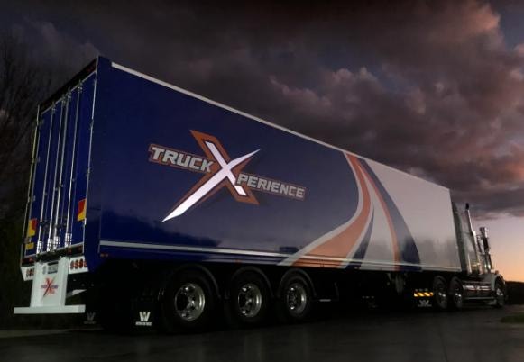 Truck Xperience branded semi-trailer at dusk